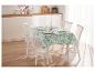 Table avec nappe à fleurs et chaises blanches.