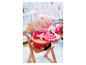 Un doudou de Peppa Pig assis sur une chaise haute avec une assiette rose.