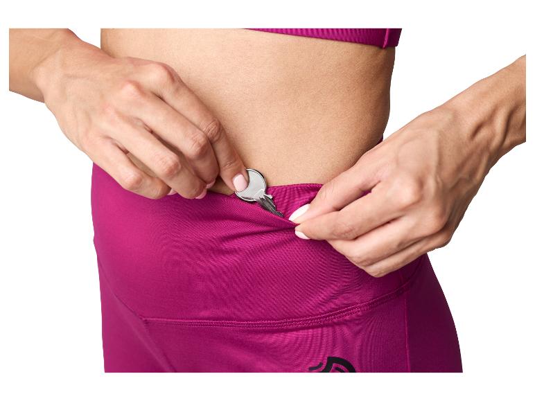 Femme mettant une clé dans la poche cachée de son legging de sport magenta.