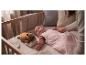 Bébé en gigoteuse rose étoilée, dans un berceau avec une peluche lumineuse.
