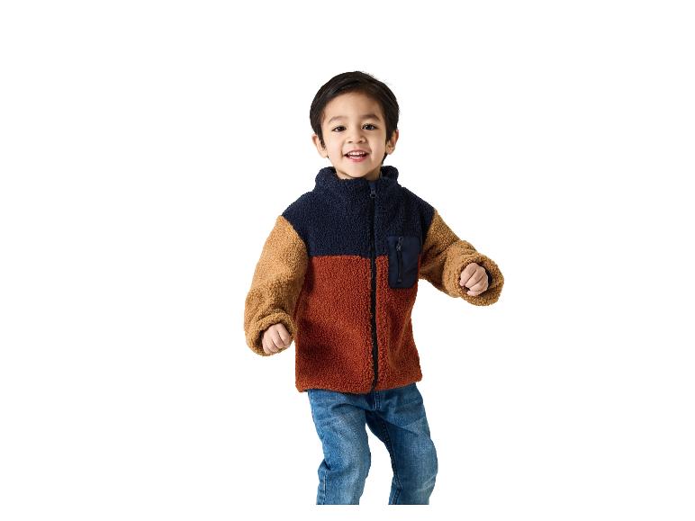 Garçon souriant en veste polaire color block et jean