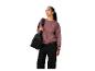 Femme en sweat-shirt rose et pantalon noir, avec un sac de sport noir sur l'épaule.