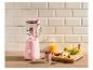 Mixeur rose avec des fruits et un smoothie sur une table en bois.