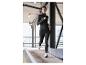 Une femme en tenue de sport noire Craft en train de courir.