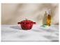 Cocotte en fonte rouge, bouteille d'huile d'olive et bol de ciboulette sur un comptoir en marbre.