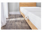 Un matelas blanc sur un sommier en bois, sur un plancher en bois.