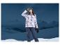 Femme en veste de ski Mountain Slope et pantalon dans un paysage enneigé.