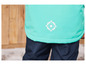 Une veste turquoise avec une fleur blanche et un pantalon bleu foncé.
