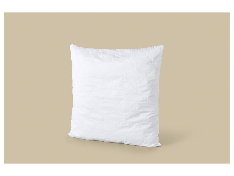 Oreiller blanc matelassé sur fond beige