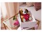 Un chien en peluche tenant un cœur dans une boîte blanche sur une table en verre.