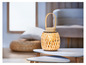 Une lampe en bois avec un design tressé sur une table basse blanche.