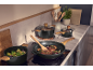 Casseroles et poêles noires avec poignées en bois sur une plaque à induction dans la cuisine.