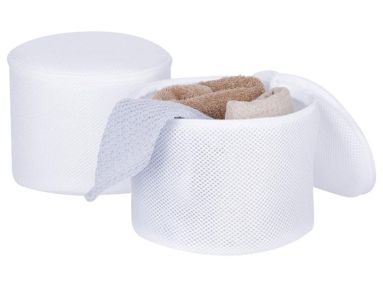 Deux sacs de lavage en maille blanche, l'un fermé et l'autre ouvert avec des serviettes