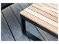 Banc en bois avec cadre en métal noir sur une terrasse en bois.