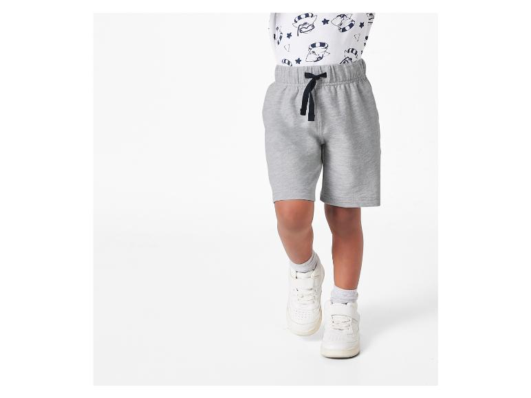 Un garçon portant un short de jogging gris et des baskets blanches.