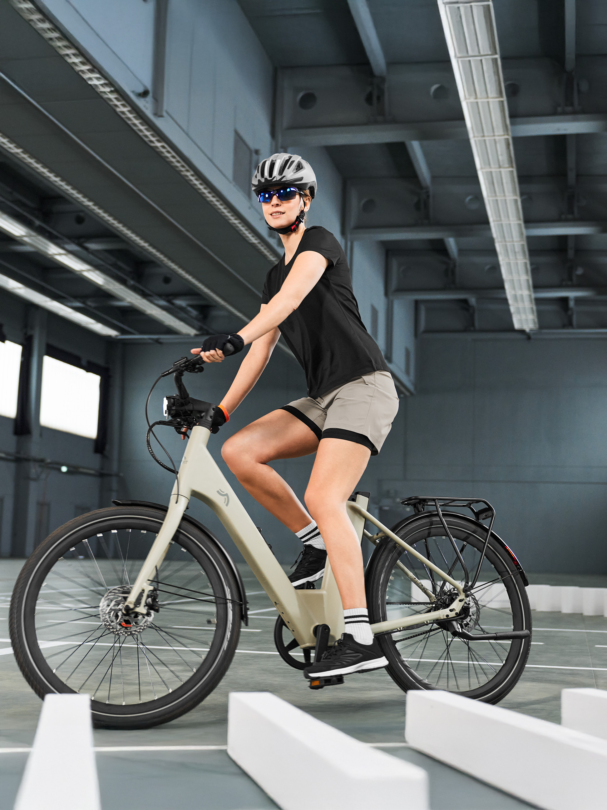 Femme en tenue de cyclisme sur un vélo électrique, naviguant sur un parcours intérieur.