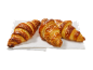 Trois croissants dorés aux cristaux de sucre sur une serviette blanche.