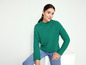 Une femme portant un pull vert et un jean bleu.