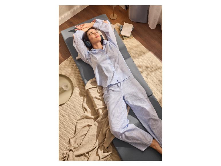Femme se relaxant sur un lit pliant en écoutant de la musique.