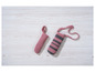 Deux porte-bouteilles en tricot rose, l'un avec une bandoulière, sur une table en bois.