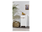 Meuble de rangement blanc avec un tiroir et une porte, à côté d'un panier et d'une plante.