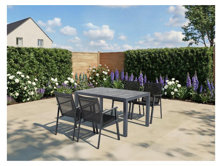 Ensemble de salle à manger d'extérieur avec table à lattes grise et quatre chaises sur une terrasse, entouré de verdure et de fleurs.