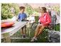 Mère et fils en camping avec une table pliante, des chaises et une glacière.