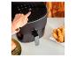 Une friteuse à air noire Cecotec avec du poulet et du saumon frits.