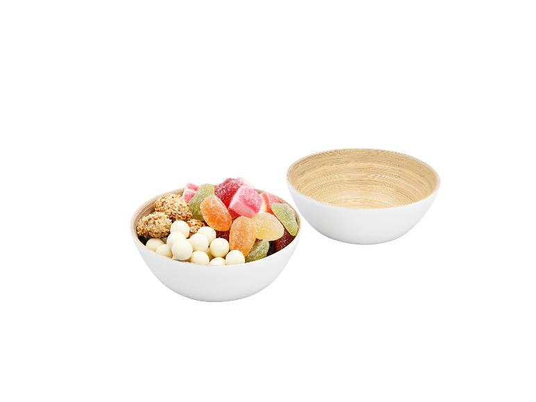 Deux bols blancs, l'un rempli de bonbons et de snacks colorés, l'autre vide.