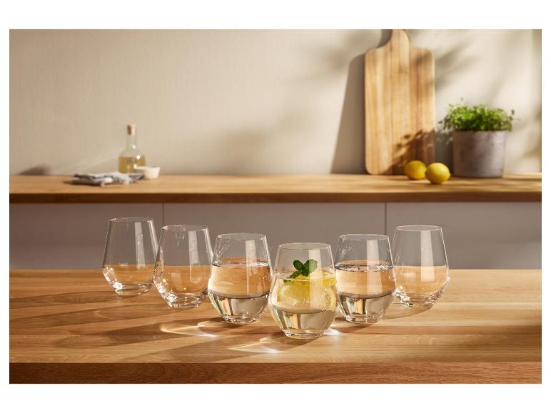 Six verres d'eau sur une table en bois, un avec du citron et de la menthe.