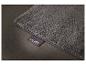 Tapis de bain gris moelleux avec une étiquette de marque sur un sol sombre.