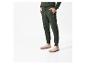 Homme portant un pantalon de survêtement vert avec le logo Lacoste et des baskets blanches.
