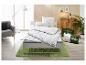 Couette et oreillers blancs Fjödur sur un lit avec tapis vert dans une chambre lumineuse.