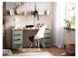 Bureau avec plateau en bois et tiroirs verts, chaise blanche, étagères et fenêtre.