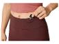 Femme rangeant des clés dans la poche de son legging bordeaux et de son haut rose.