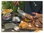 Personne plaçant un burger sur un pain avec une spatule, avec des ingrédients de barbecue sur la table.