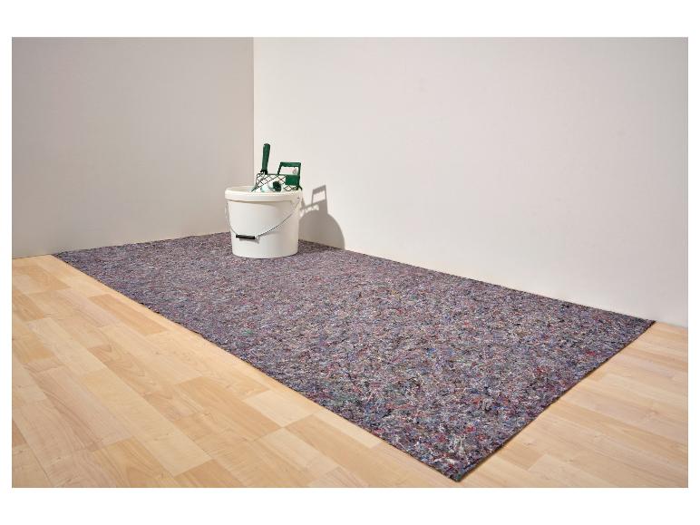 Tapis de protection de sol avec un seau et des outils de peinture dans le coin d'une pièce.