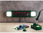 Multiprise verte avec lumières et fer à souder avec carte de circuit sur un établi.