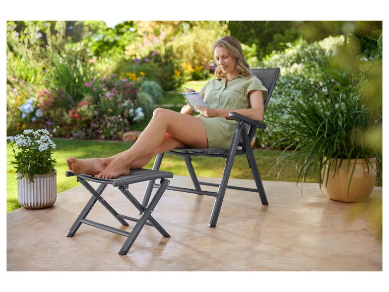 Femme se détendant sur une chaise de jardin avec repose-pieds, lisant un livre