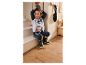Petit garçon assis sur une marche d'escalier avec des vêtements et des bottes de pluie Paw Patrol.