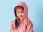 Un enfant portant un imperméable rose à imprimé arc-en-ciel.