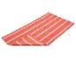 Tapis orange à rayures roses, plié sur fond blanc.