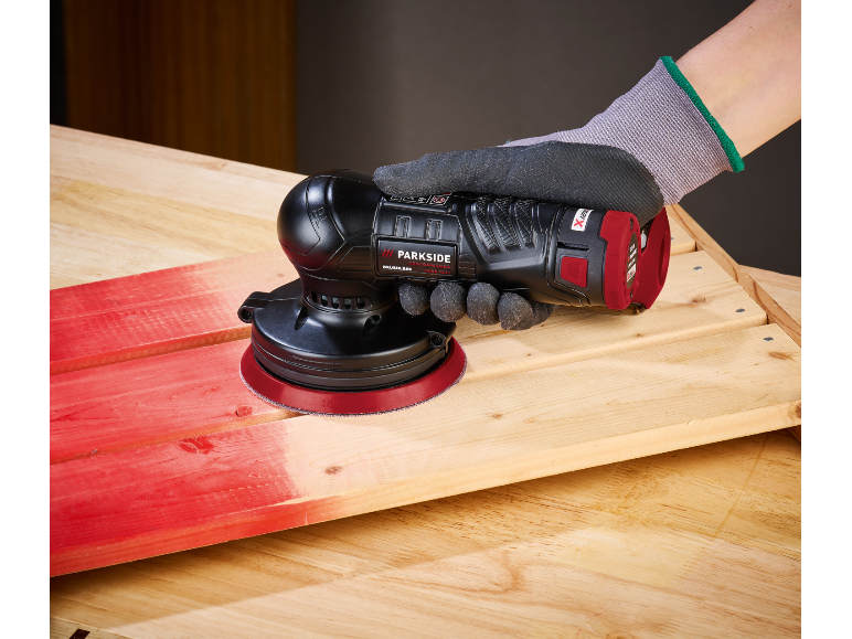 Ponceuse sans fil portative en train de poncer une surface en bois.