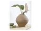 Un vase beige avec une plante, un bol et des livres sur une table en bois.