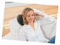 Une femme profite d'un coussin de massage sur le canapé.