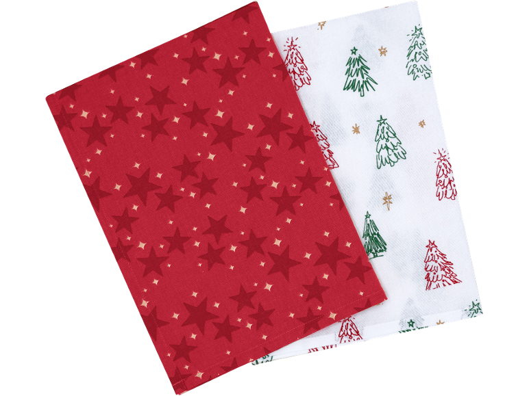 Deux torchons de cuisine de Noël : un rouge à étoiles et un blanc à sapins.