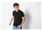 Un homme porte un t-shirt noir simple avec une poche et un jean.