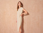 Une femme porte une robe beige légère avec une fente.