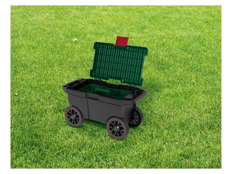 Boîte à outils roulante noire et verte avec couvercle ouvert sur une pelouse verte vibrante.