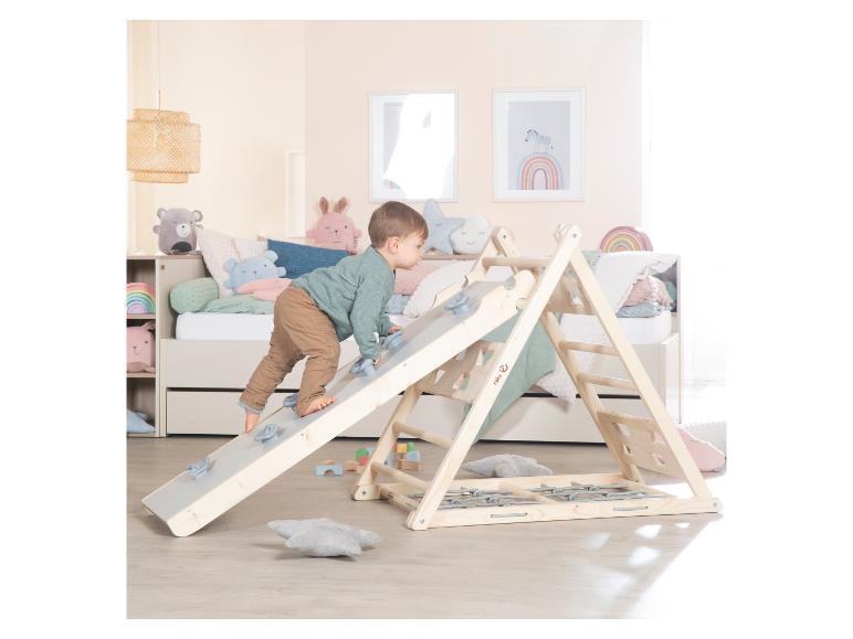 Jeune enfant grimpant sur une structure d'escalade en bois dans une chambre d'enfant avec lit et décor.